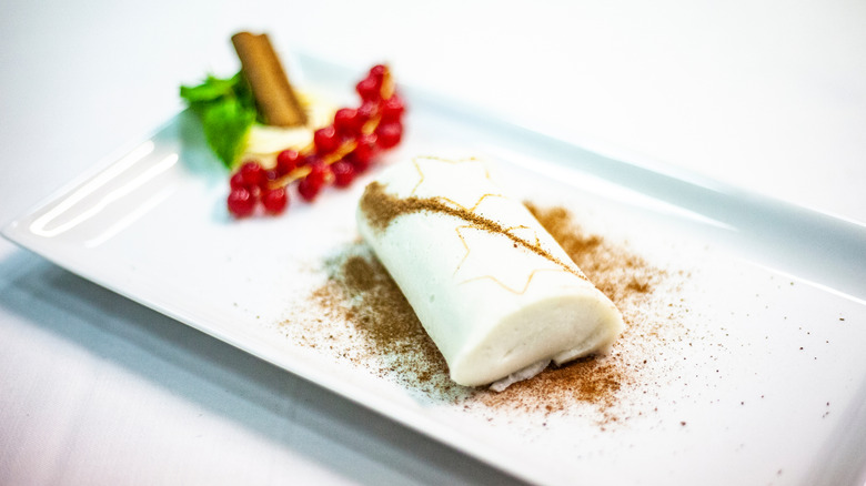 A traditional white Turkish pudding decorated with golden stars and holiday berries on a plate