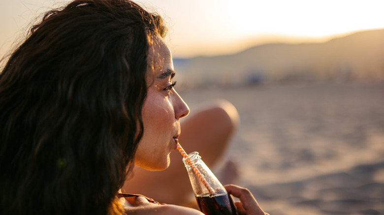 Woman drinking a soft drink from a glass bottle