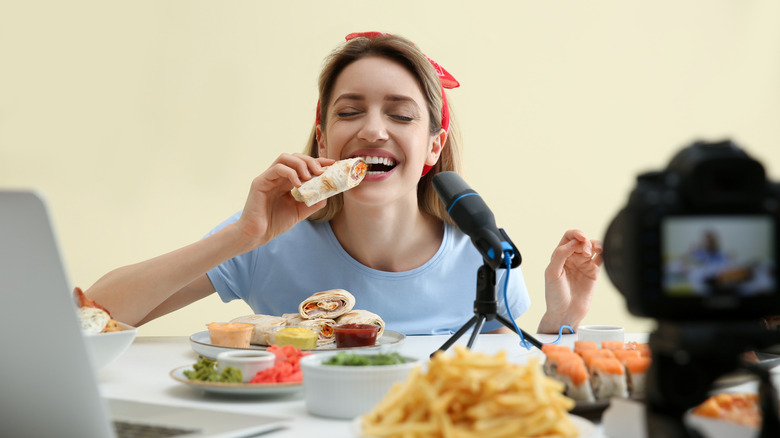 Woman posing with food pretending to eat in front of camera.