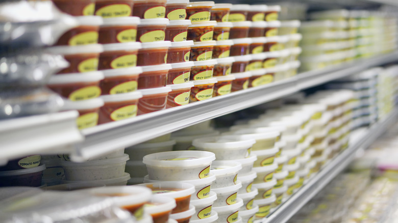 Various white red and green dips in refrigerated aisle in grocery store