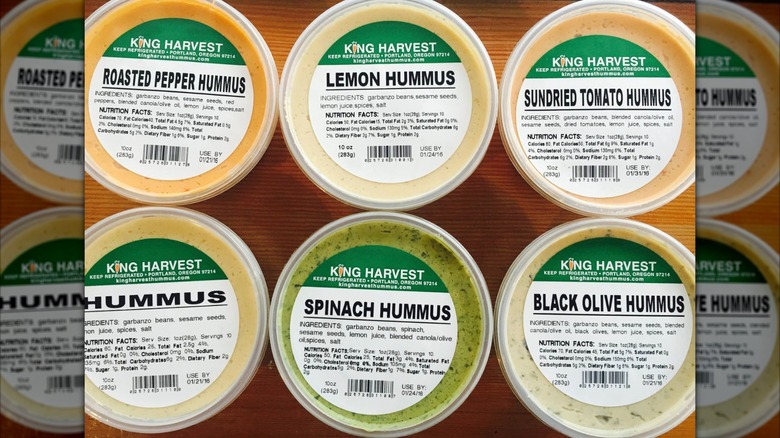 Different types of King Harvest Hummus on wooden surface