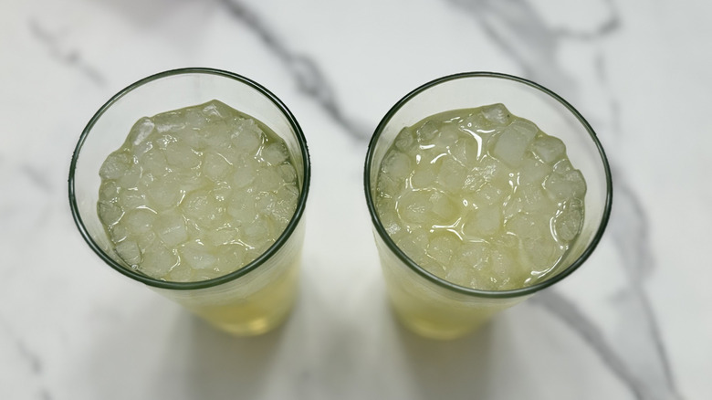 Looking down into two glasses with soda and ice on marble background