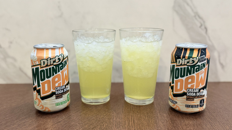 Two dirty mountain dew soda cans poured into glasses on table