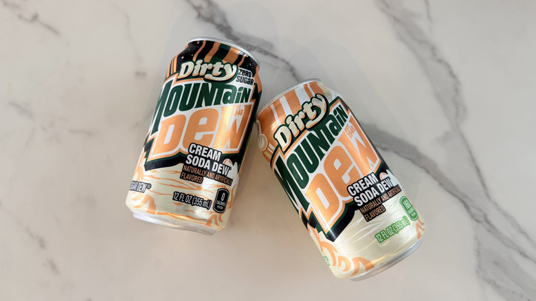 Two cans of mountain dew dirty cream soda on a marble background