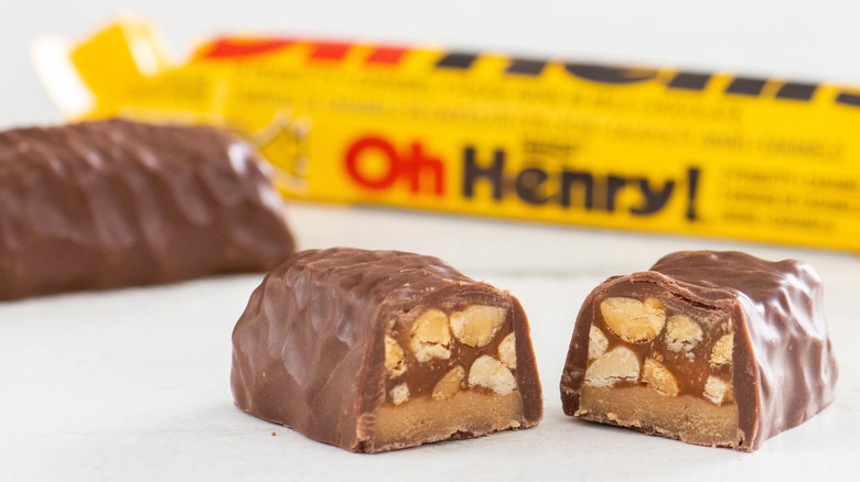 Close-up of Oh Henry! chocolate bar interior showing peanuts and caramel, with the classic yellow wrapper in the background