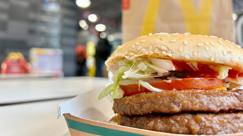 A closeup of the McPlant Burger next with a McDonald's Bag in the background