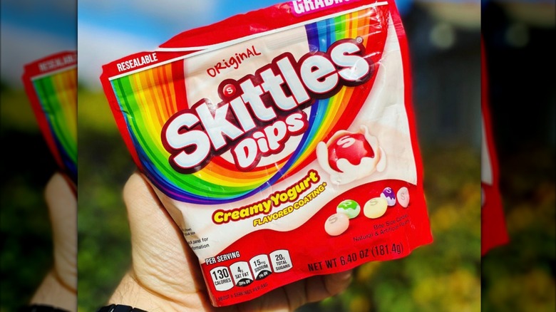 A hand holding Skittles Dips bag