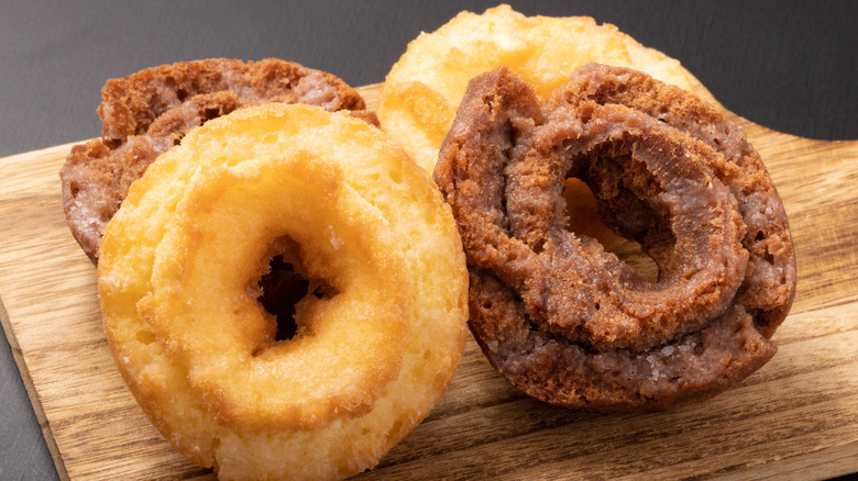 Four old-fashioned donuts with glaze in two rows with plain and chocolate flavors alternating