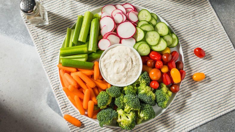 Basic veggie platter with creamy dip in center surrounded by presliced veggies