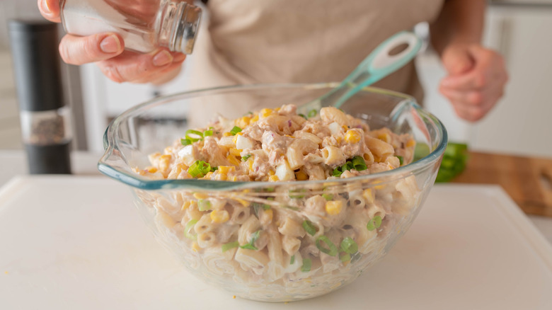 Woman salting a big bowl of tuna salad