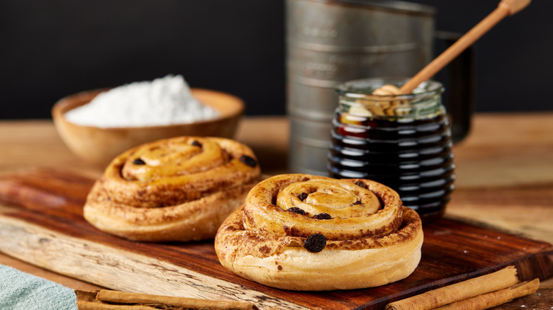 Cinnamon rolls on board with honey in background