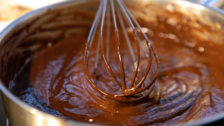 A close up of a whisk in brownie batter