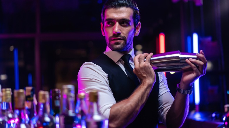 Bartender shaking cocktail in dark bar