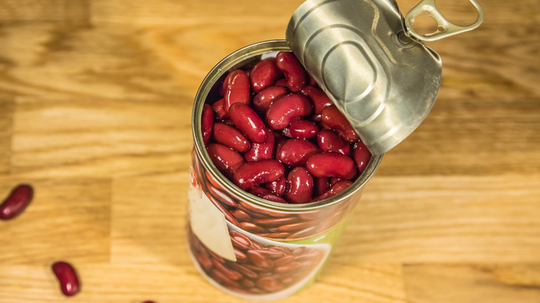 Open can of kidney beans on wooden counter