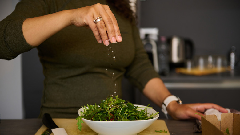 Woman sprinkling salt on salad