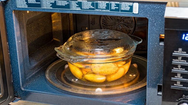 A glass pot of potatoes in a microwave
