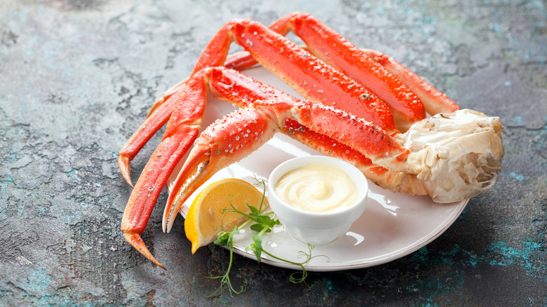 snow crab legs on plate with lemon and mayonnaise