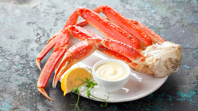 snow crab legs on plate with lemon and mayonnaise