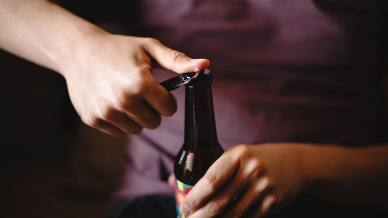 A person opening a bottle of beer.