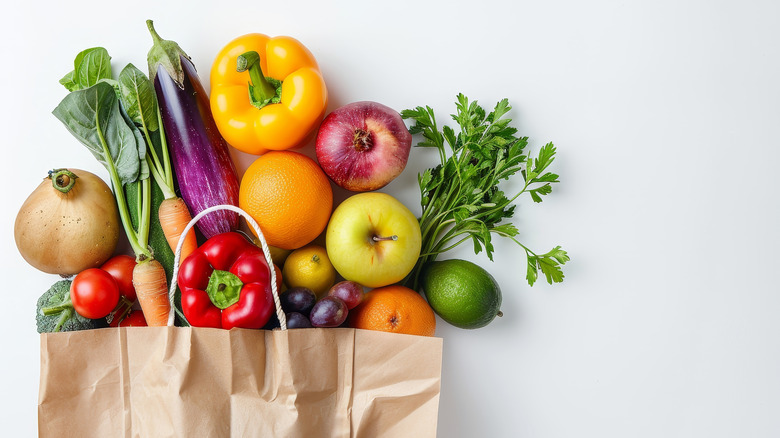 A paper grocery bag with fresh produce spilling out