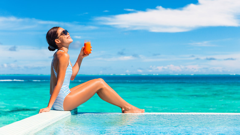 Woman drinking a glass of carrot juice at the beach