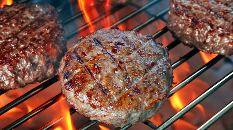 A close-up of a hamburger cooking on a hot grill