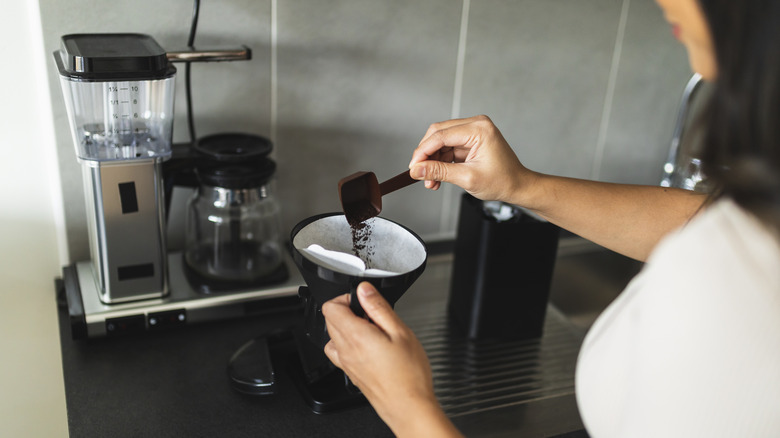 Woman pours coffee grounds onto paper filter