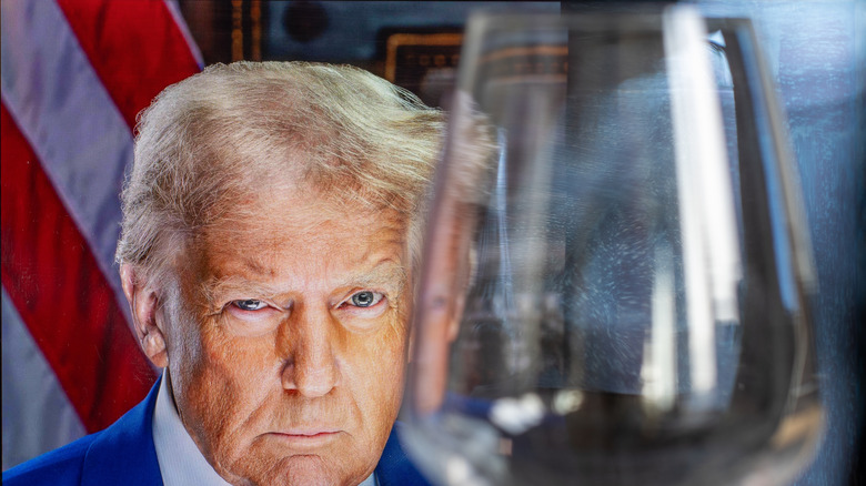 Donald Trump in the background, empty wine glass in the foreground