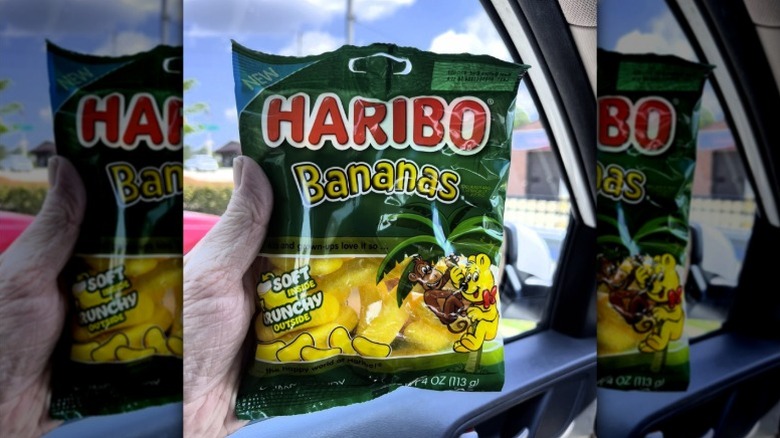 Someone holding a bag of Haribo Bananas while sitting in their car.