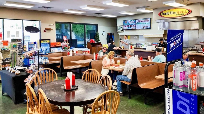 Inside of diner showing people in booths and a Frank Allen Grill sign