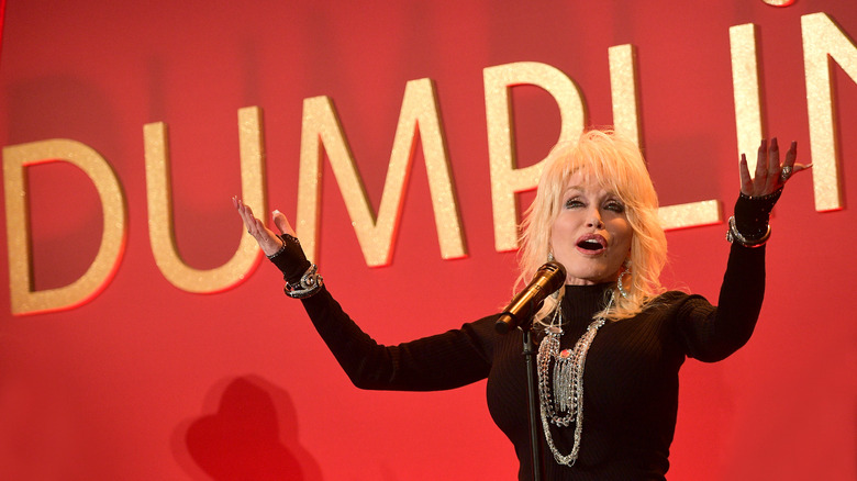Dolly Parton on stage in front of Dumplin' sign.