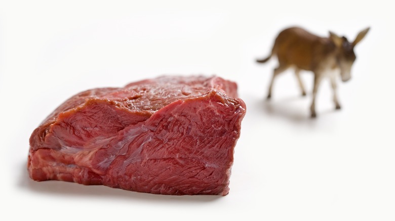 Chunk of red meat with donkey in background
