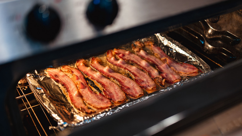 Bacon cooking on foiled sheet pan in an oven