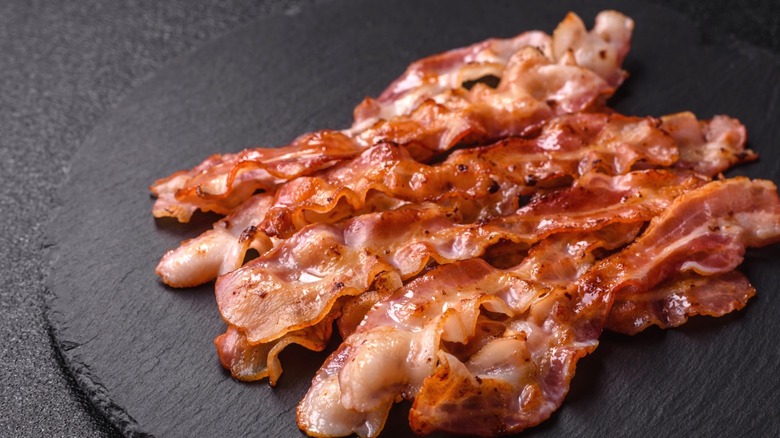 Several slices of bacon on a dark surface
