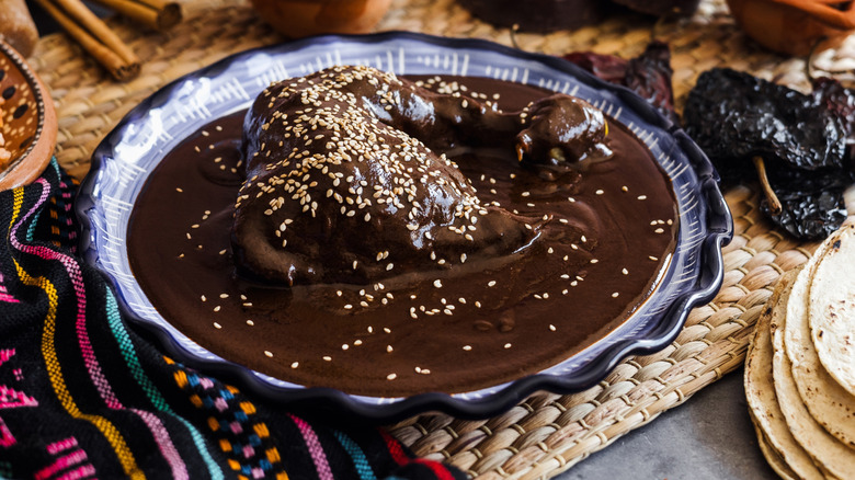 Mole Poblano, a Mexican sauce that includes chocolate, covering a piece of meat on a plate.