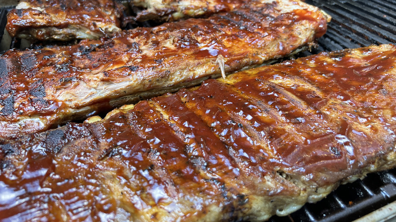 Barbecue sauce-coated ribs cooking on a grill