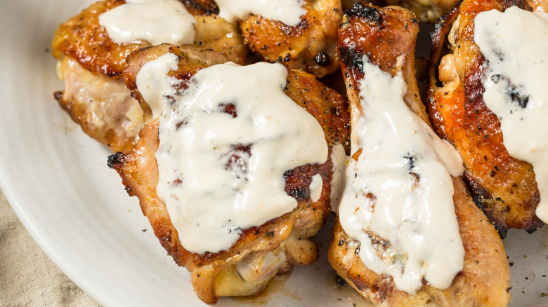 Grilled chicken thighs with Alabama white sauce served on a plate