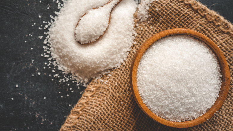 Granulated salt in a wooden bowl and spoon on burlap