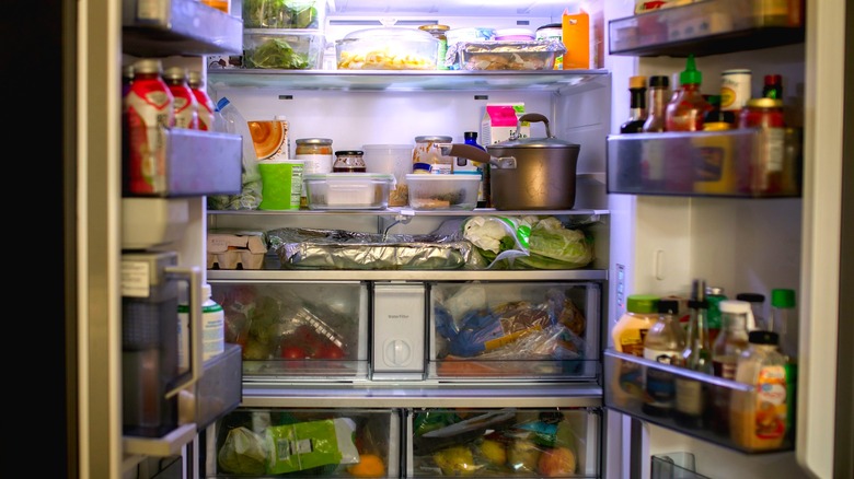 The inside of a refrigerator, packed with food, drinks, and condiments