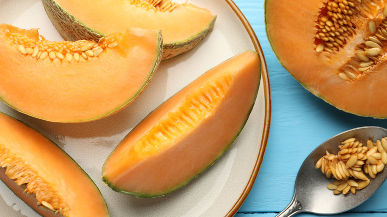 Slices of cantaloupe on a plate and seeds on a spoon