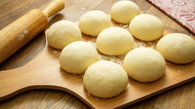 Balls of homemade pizza dough on a wooden chopping board