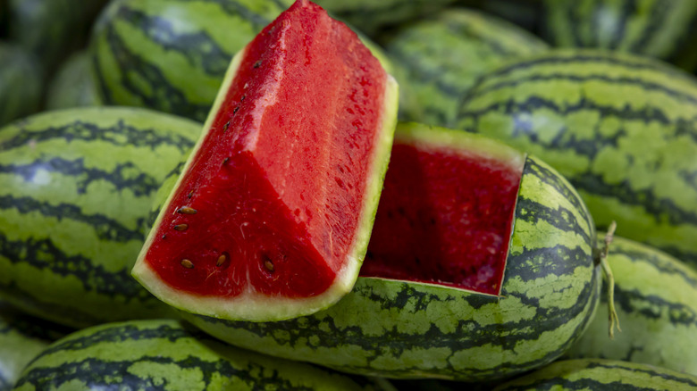 A watermelon wedge with whole watermelons