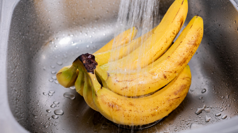 A bunch of bananas being washed in a sink