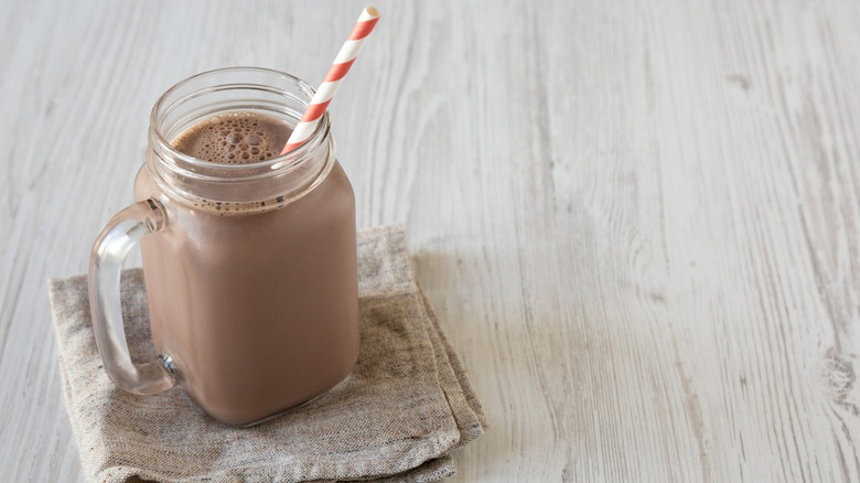 Glass jar of chocolate milk with straw