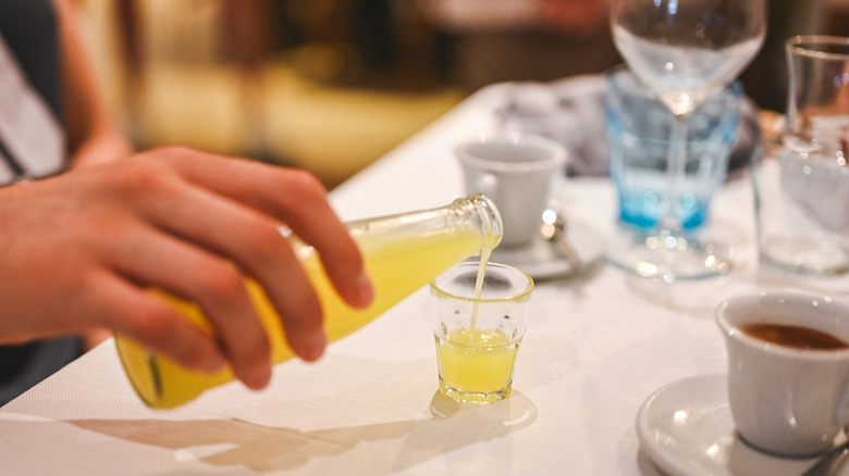 hand pouring citrus liqueur into a shot glass
