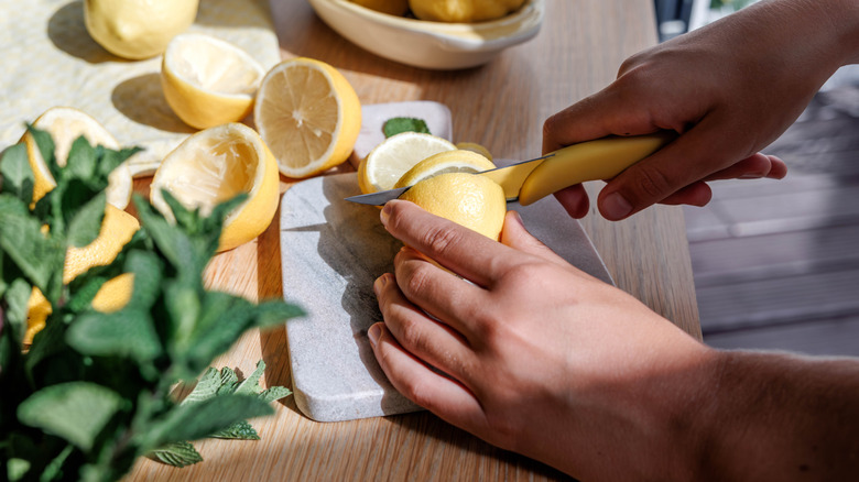 hands using a knife to cut lemons