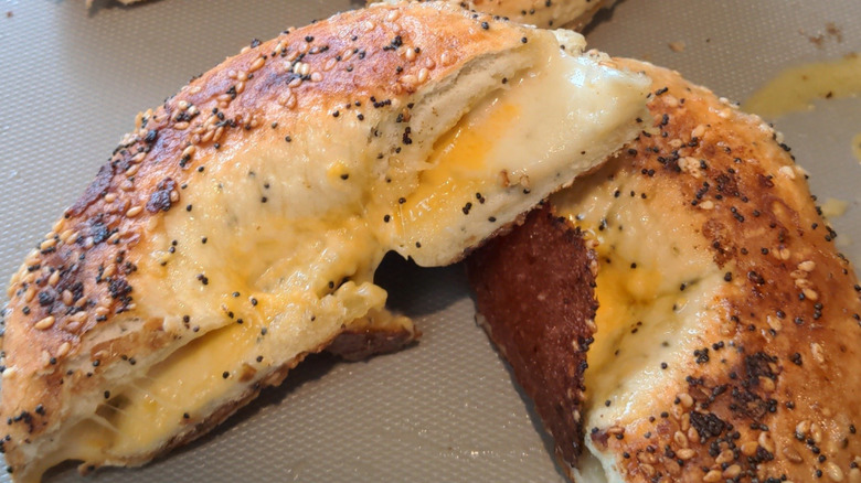 A seeded bagel grilled cheese sliced in half showing melty cheese