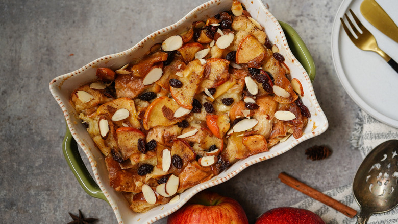 A bread pudding made from bagels, apples, nuts, and raisins in a rectangular white dish