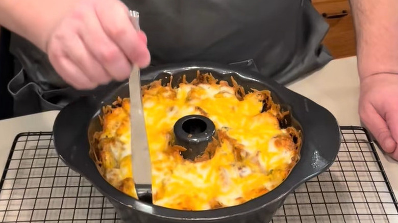 A Bundt pan filled with cooked pull-apart garlic bagels on a cooling rack