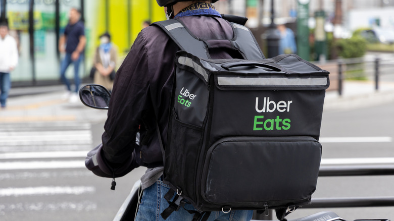 An Uber Eats delivery worker from behind wearing an Uber Eats backpack